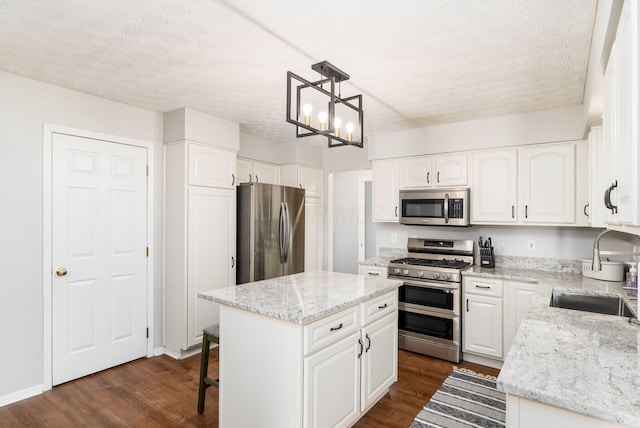 kitchen featuring dark wood finished floors, a textured ceiling, appliances with stainless steel finishes, and a sink