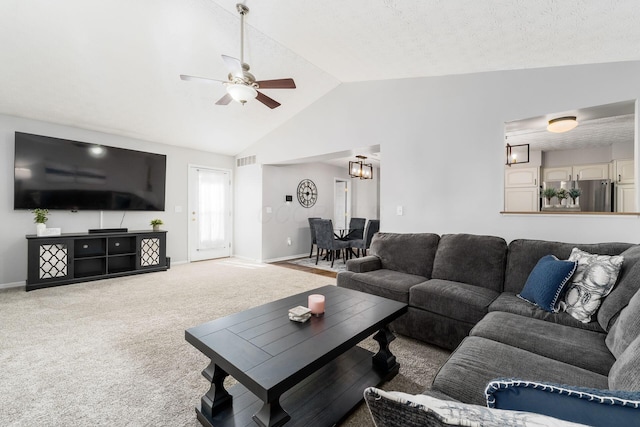carpeted living room with baseboards, vaulted ceiling, visible vents, and ceiling fan with notable chandelier