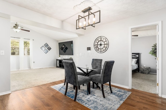 dining room with wood finished floors, a textured ceiling, and ceiling fan with notable chandelier