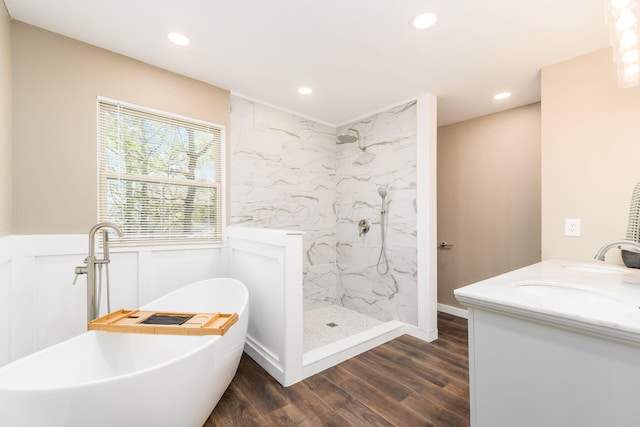 bathroom with recessed lighting, wood finished floors, a soaking tub, and a marble finish shower