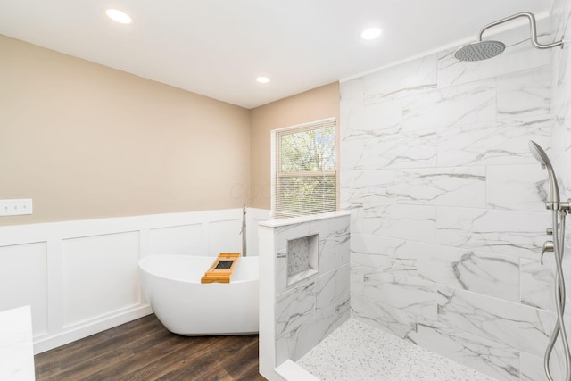 bathroom with a decorative wall, a marble finish shower, wainscoting, a freestanding bath, and recessed lighting