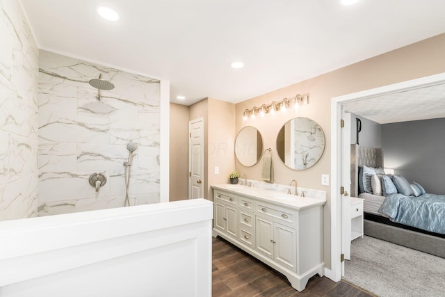 full bathroom featuring double vanity, wood finished floors, a sink, and a marble finish shower