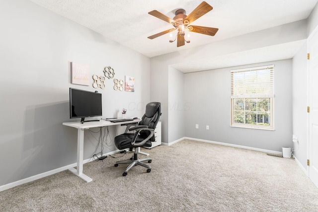 carpeted office space featuring baseboards and a ceiling fan