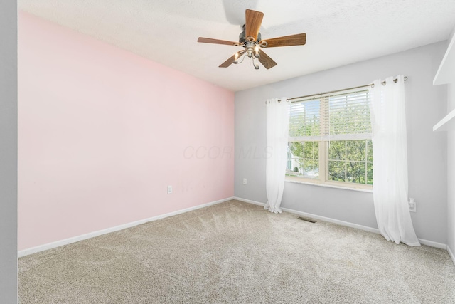 carpeted empty room featuring ceiling fan, baseboards, and visible vents