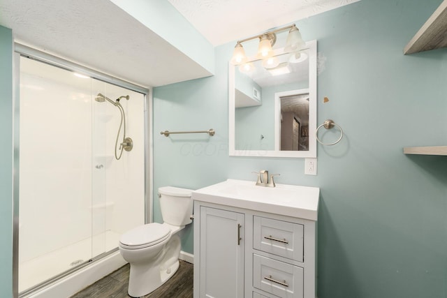 bathroom with vanity, wood finished floors, a shower stall, and toilet