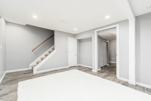 finished basement with recessed lighting, wood finished floors, stairs, and baseboards