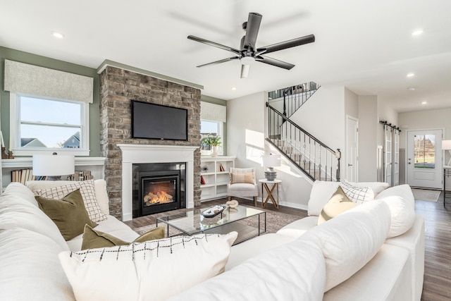living area featuring stairway, recessed lighting, a fireplace, wood finished floors, and a ceiling fan