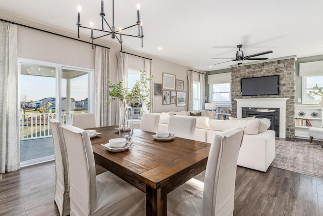 dining room with a fireplace, a wealth of natural light, dark wood-style floors, and ceiling fan with notable chandelier