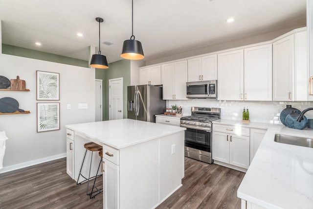 kitchen featuring a sink, stainless steel appliances, dark wood-type flooring, a center island, and backsplash