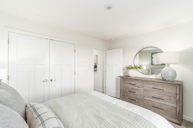 carpeted bedroom featuring a closet and baseboards