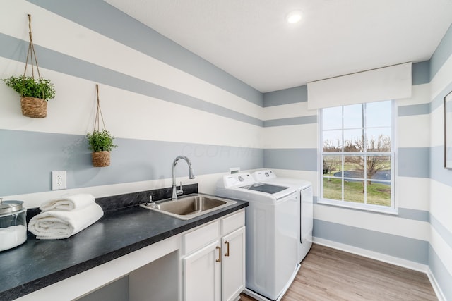 laundry room with cabinet space, a sink, baseboards, light wood-type flooring, and washer and clothes dryer