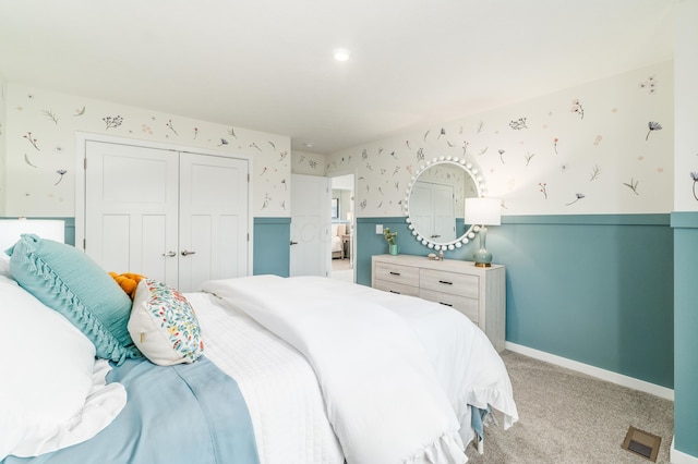 bedroom featuring baseboards, wallpapered walls, light colored carpet, and a closet