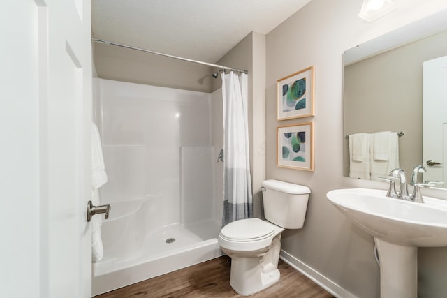 bathroom featuring baseboards, wood finished floors, toilet, and a shower with curtain