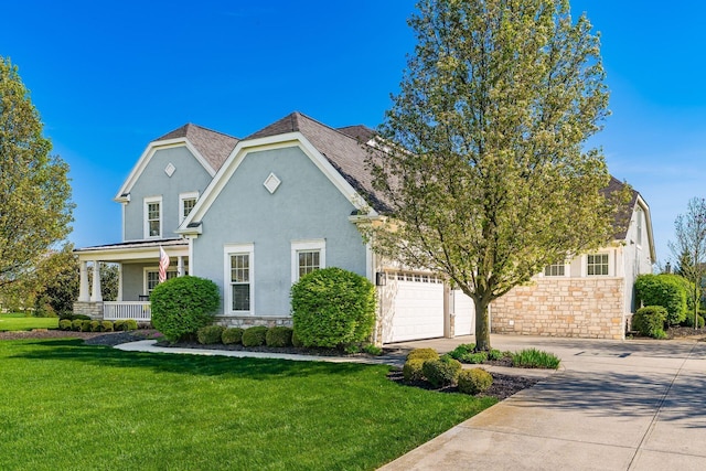 traditional home with a front lawn, stone siding, covered porch, concrete driveway, and stucco siding