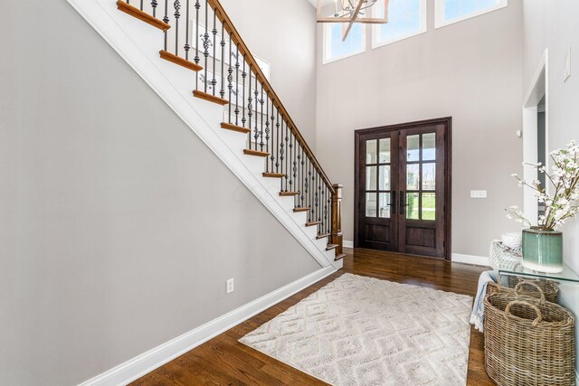 entrance foyer featuring wood finished floors, baseboards, a notable chandelier, and stairway