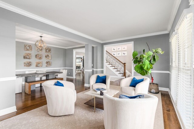 living area featuring wood finished floors, crown molding, and stairs