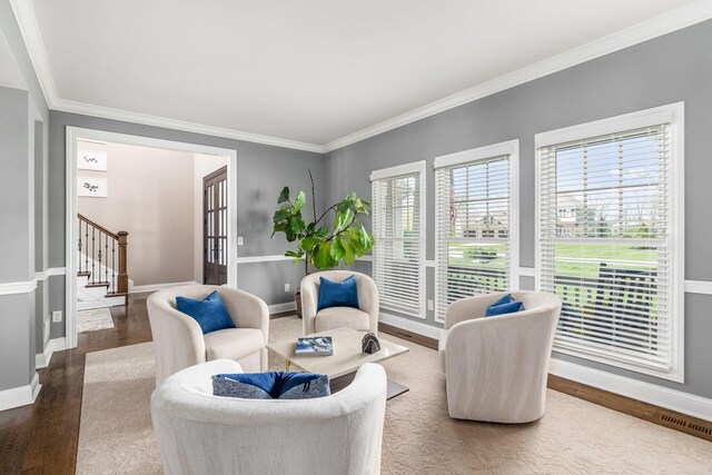 sitting room with wood finished floors, stairs, baseboards, and ornamental molding