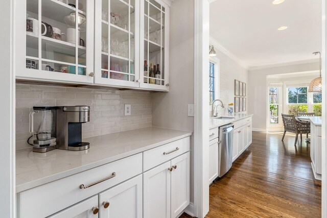 bar featuring stainless steel dishwasher, dark wood-style flooring, baseboards, decorative backsplash, and ornamental molding