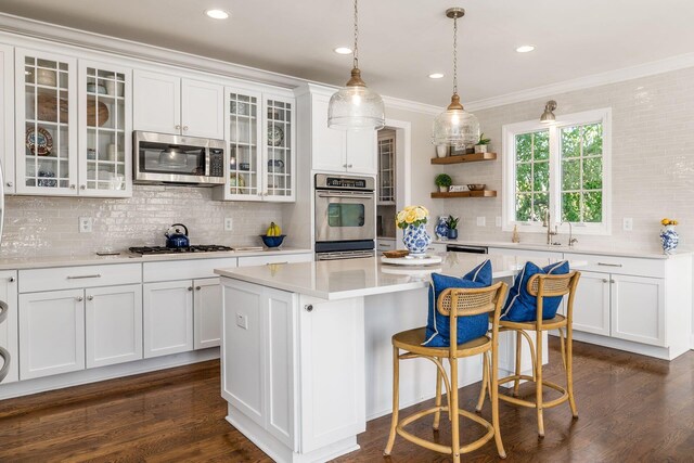 kitchen featuring white cabinets, stainless steel appliances, light countertops, tasteful backsplash, and dark wood-style flooring