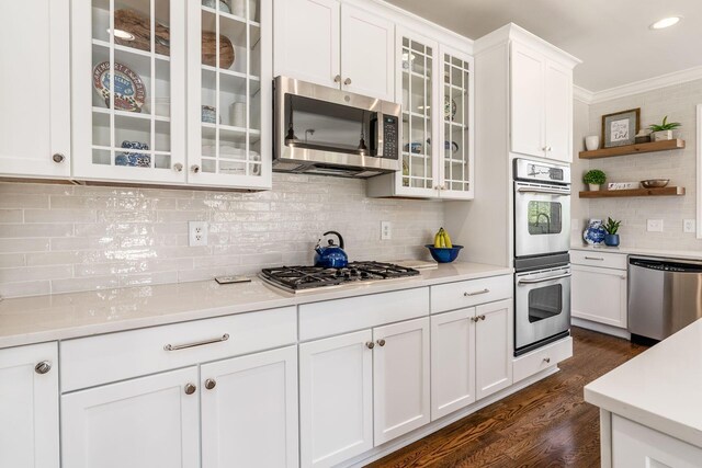 kitchen with white cabinets, stainless steel appliances, dark wood-style floors, tasteful backsplash, and light countertops
