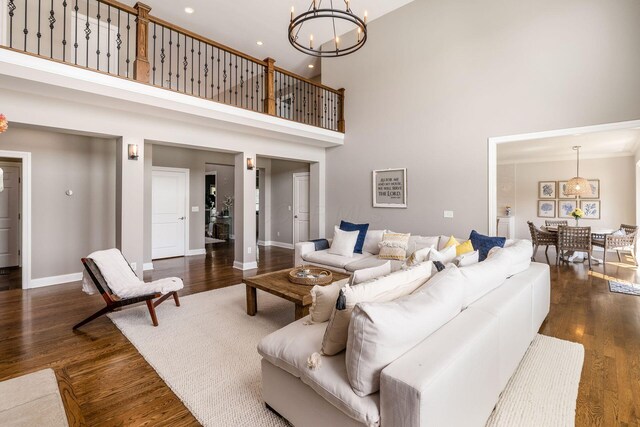 living area with a chandelier, baseboards, a high ceiling, and dark wood-type flooring