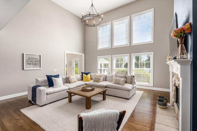 living area featuring wood finished floors, a towering ceiling, baseboards, and a notable chandelier