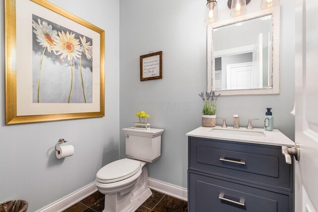bathroom featuring vanity, toilet, and baseboards