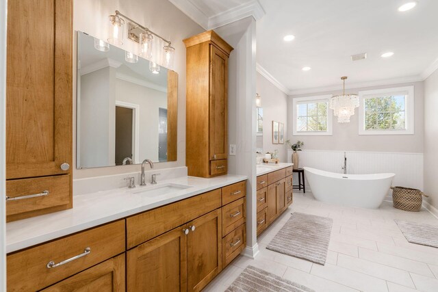 full bathroom featuring two vanities, a freestanding tub, crown molding, and a sink