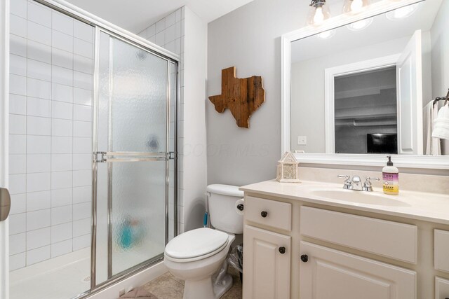 bathroom featuring toilet, vanity, and a stall shower