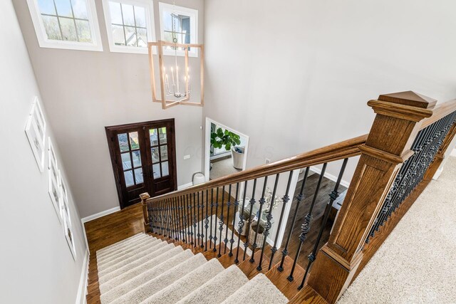 stairs featuring french doors, baseboards, a wealth of natural light, and a notable chandelier
