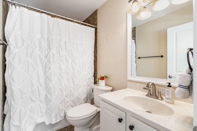 bathroom with shower / bath combination with curtain, toilet, and vanity