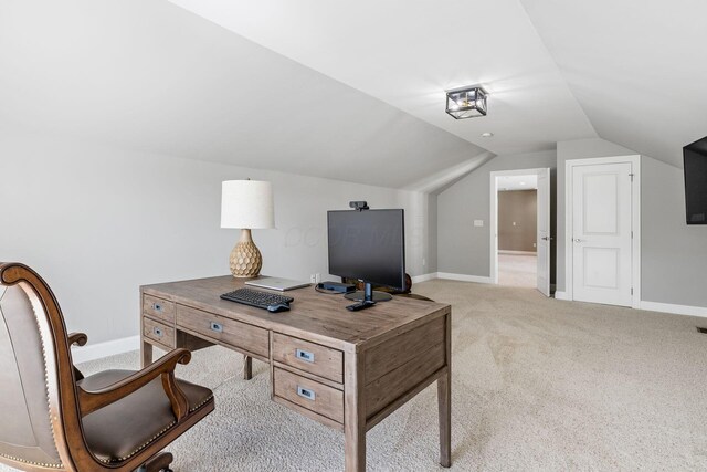 office featuring lofted ceiling, light carpet, and baseboards