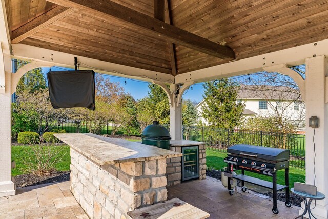 view of patio featuring fence, a grill, exterior kitchen, and wine cooler