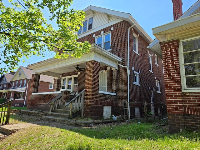 view of front of property featuring fence, a ceiling fan, and brick siding