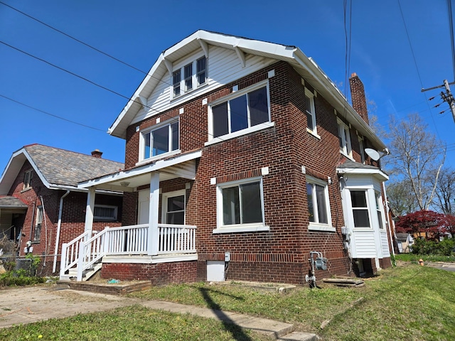 view of home's exterior with a chimney, central air condition unit, covered porch, a yard, and brick siding