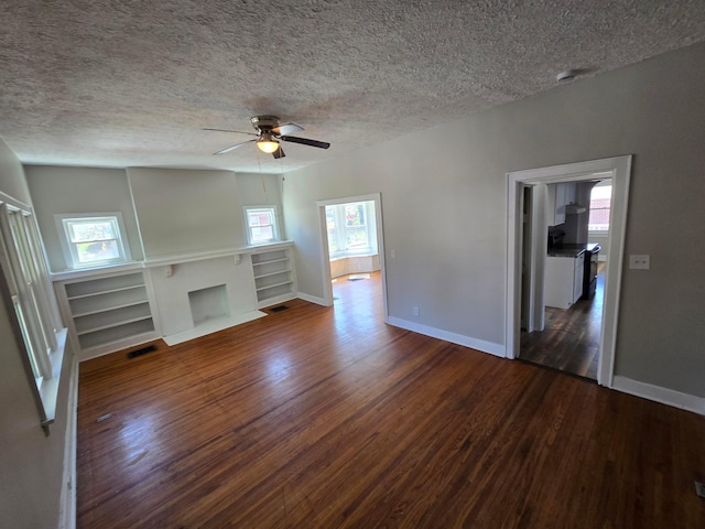 unfurnished living room with a fireplace with flush hearth, baseboards, wood finished floors, and a textured ceiling