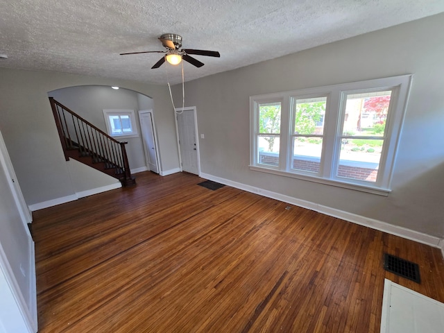 interior space featuring arched walkways, baseboards, visible vents, a ceiling fan, and hardwood / wood-style floors