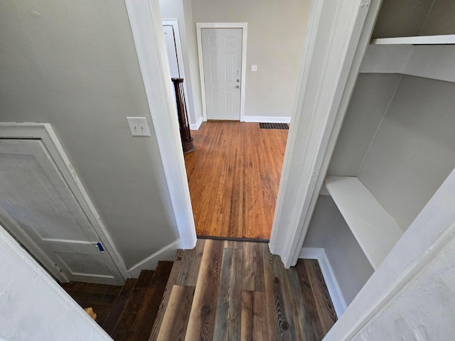 interior space featuring wood finished floors, visible vents, baseboards, and stairs