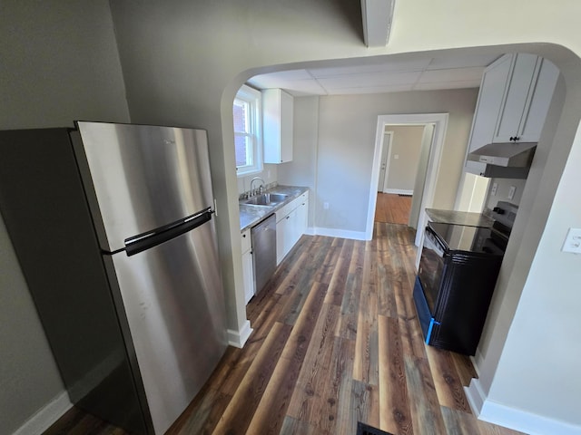 kitchen featuring white cabinets, arched walkways, appliances with stainless steel finishes, and a sink
