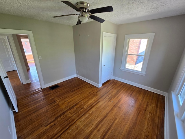 unfurnished bedroom featuring dark wood finished floors, visible vents, a ceiling fan, baseboards, and a textured ceiling