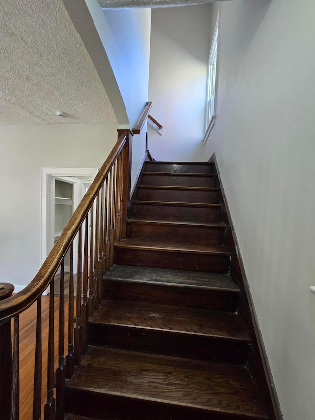 staircase featuring a textured ceiling