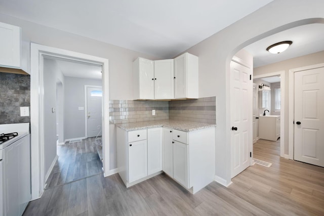 2575 Jordan Rd, Columbus, OH 43231 - kitchen featuring arched walkways, light wood-style floors, decorative backsplash, and white cabinetry