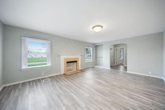 2575 Jordan Rd, Columbus, OH 43231 - unfurnished living room featuring arched walkways, baseboards, visible vents, wood finished floors, and a fireplace