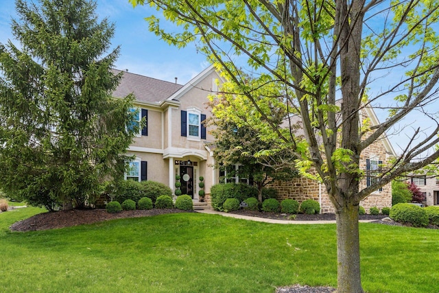 view of front facade with a front lawn, stone siding, and stucco siding