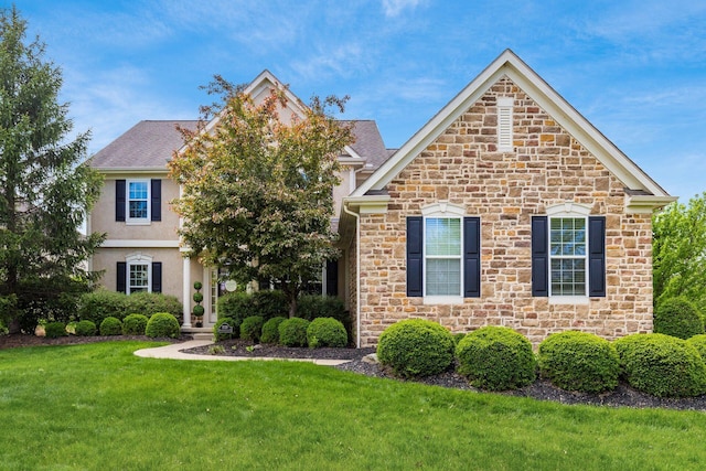 view of front of home with stucco siding, a front yard, and stone siding
