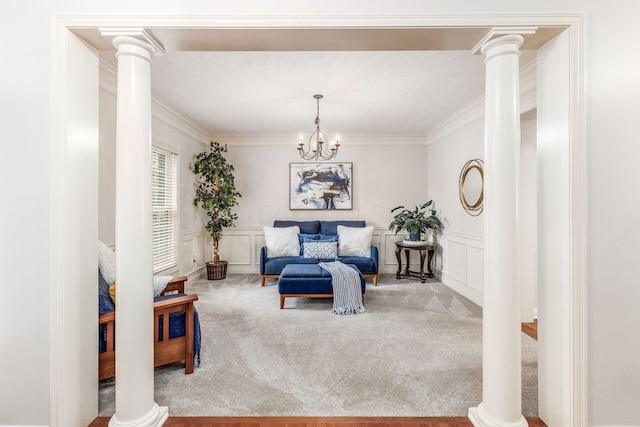 sitting room with ornate columns, ornamental molding, carpet, and a decorative wall
