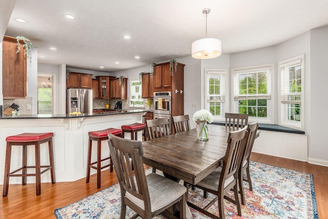 dining area with light wood-type flooring, recessed lighting, and baseboards