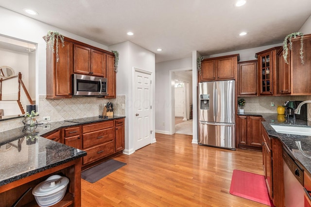 kitchen with backsplash, stainless steel appliances, a sink, and light wood-style floors