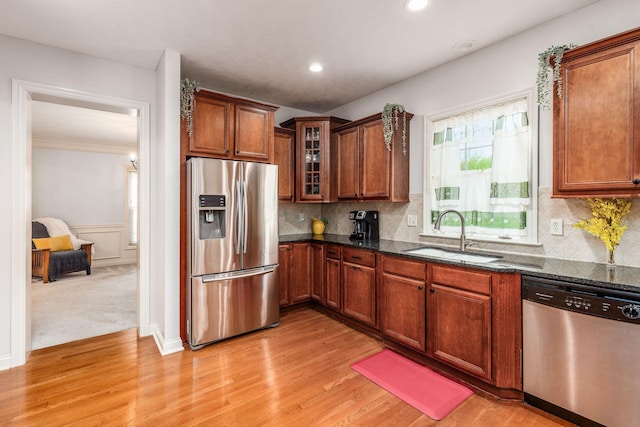 kitchen with a sink, dark stone counters, appliances with stainless steel finishes, and a wealth of natural light