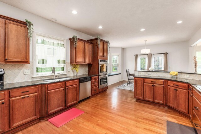 kitchen with light wood-type flooring, a sink, decorative backsplash, and stainless steel appliances
